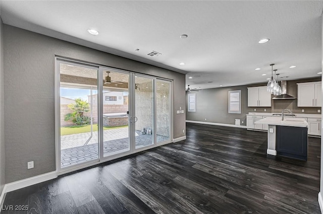 kitchen featuring baseboards, light countertops, dark wood-style floors, and wall chimney range hood