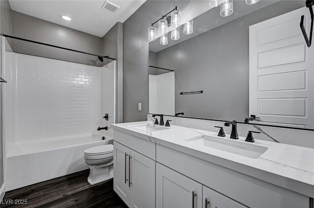 full bathroom featuring toilet, visible vents, a sink, and wood finished floors