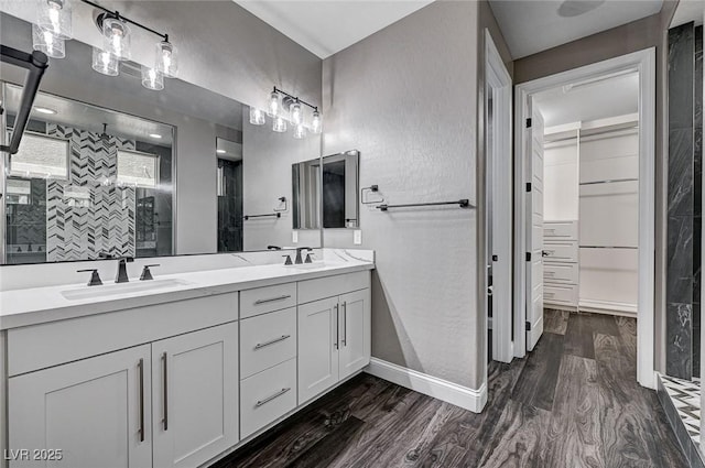 full bathroom with double vanity, a shower stall, a sink, and wood finished floors