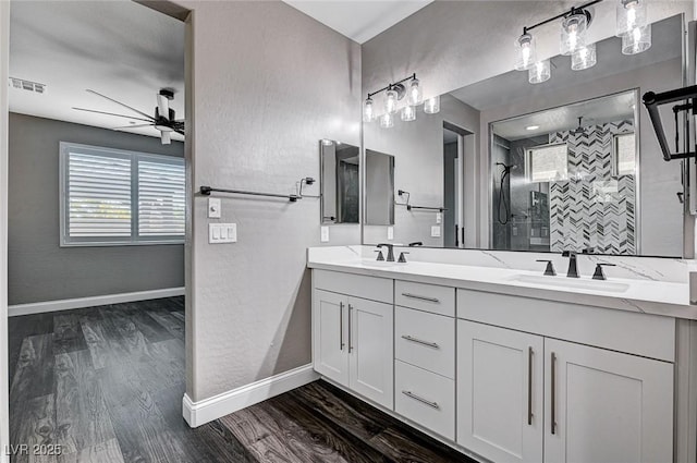 full bath featuring ceiling fan, a sink, wood finished floors, visible vents, and a stall shower