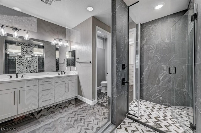 full bathroom featuring a sink, a stall shower, toilet, and double vanity
