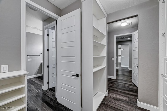 hallway with baseboards, a textured ceiling, and dark wood finished floors