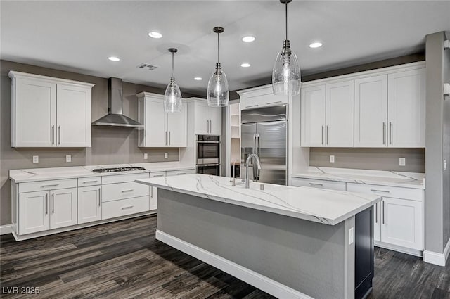 kitchen featuring wall chimney range hood, white cabinets, dark wood-style flooring, stainless steel appliances, and visible vents