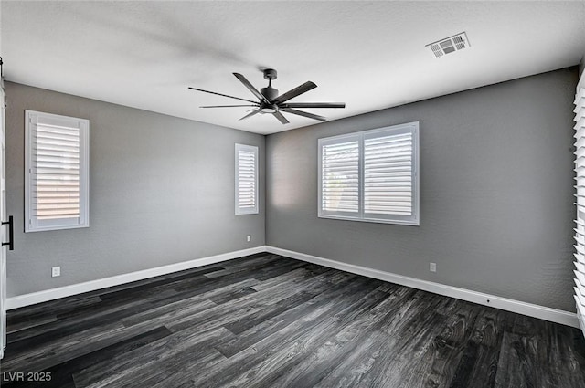spare room featuring baseboards, ceiling fan, dark wood-style floors, and visible vents
