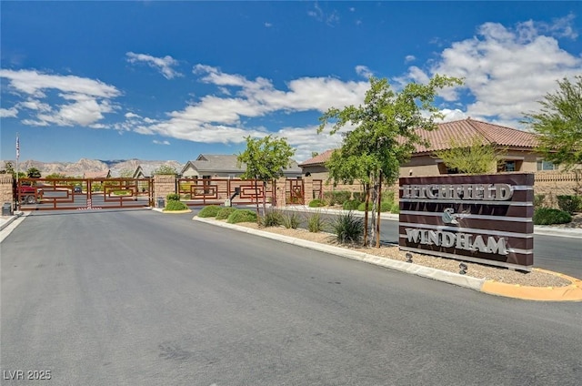 view of street with a gate, a gated entry, a mountain view, and curbs