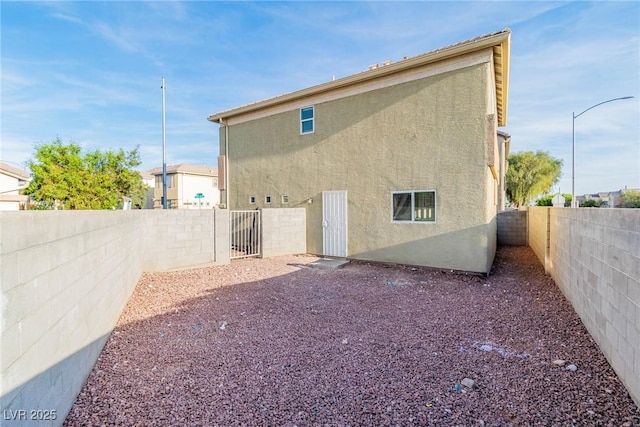 4195 Story Rock St, Las Vegas, NV 89115 - rear view of house with a fenced backyard, stucco siding, and a gate