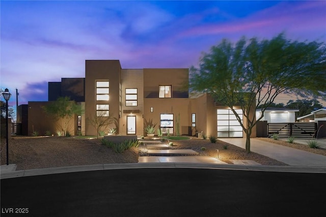 contemporary house with concrete driveway, fence, and stucco siding