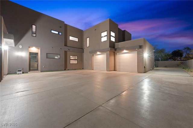 view of front facade with an attached garage, driveway, and stucco siding