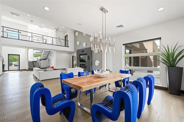 dining space with a high ceiling, a chandelier, visible vents, and light wood-type flooring