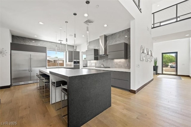 kitchen with wall chimney range hood, visible vents, modern cabinets, gray cabinetry, and stainless steel appliances