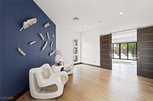 sitting room featuring visible vents, a barn door, baseboards, light wood-style floors, and recessed lighting