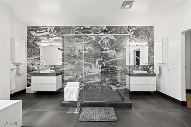 bathroom featuring visible vents, a marble finish shower, and vanity