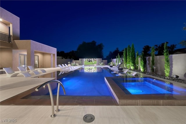 pool at night with a fenced in pool, a patio, and an in ground hot tub
