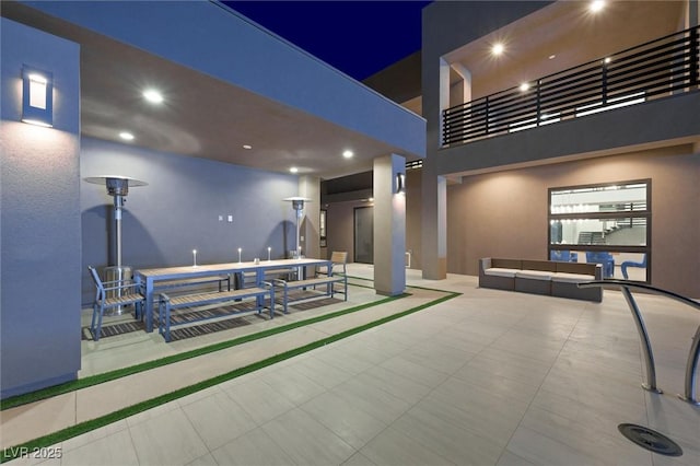 patio at twilight featuring a balcony, outdoor dining area, and an outdoor hangout area