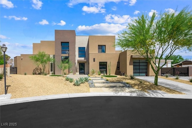view of front facade with concrete driveway, stucco siding, fence, and a garage