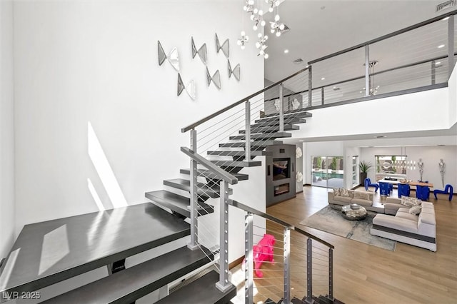 stairs with wood finished floors and a towering ceiling