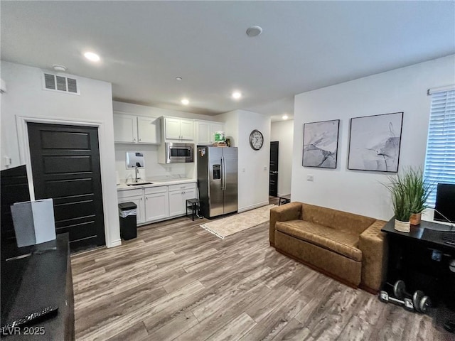 living room with recessed lighting, light wood finished floors, and visible vents