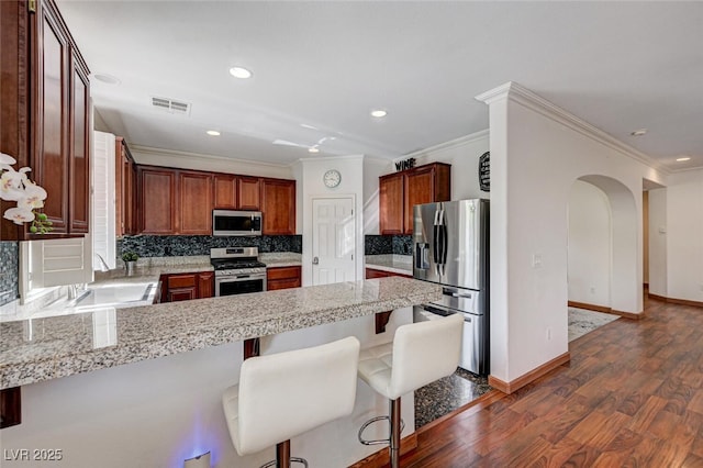 10519 Bella Camrosa Dr, Las Vegas, NV 89141 - kitchen with arched walkways, dark wood finished floors, stainless steel appliances, visible vents, and ornamental molding
