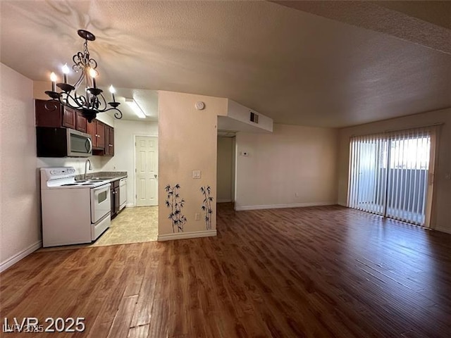 kitchen with electric range, light wood-style floors, baseboards, stainless steel microwave, and a chandelier