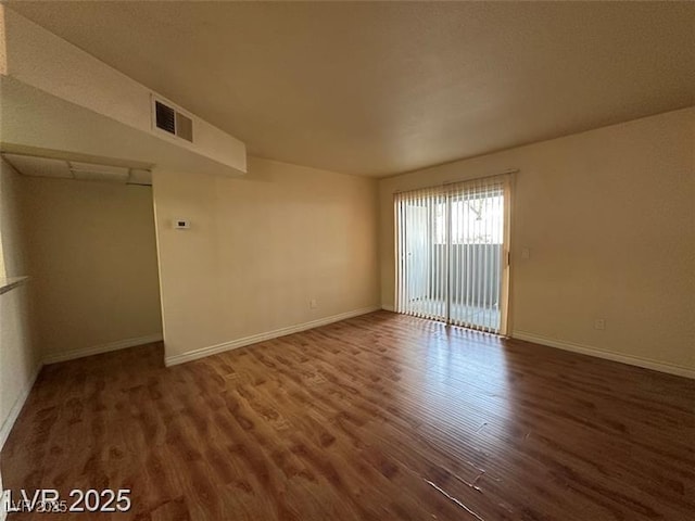empty room featuring visible vents, baseboards, and wood finished floors