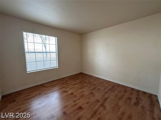spare room featuring baseboards and wood finished floors