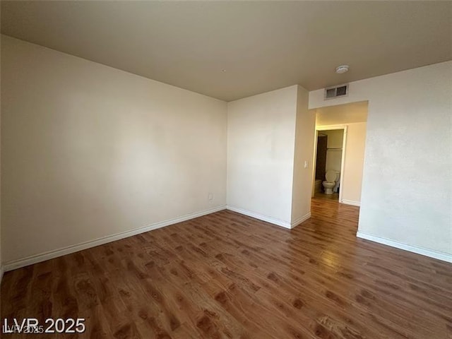 empty room featuring baseboards, visible vents, and wood finished floors