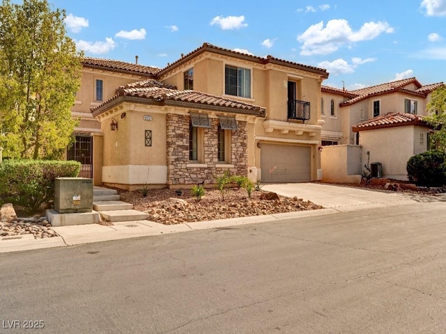 mediterranean / spanish home featuring an attached garage, stucco siding, stone siding, and concrete driveway