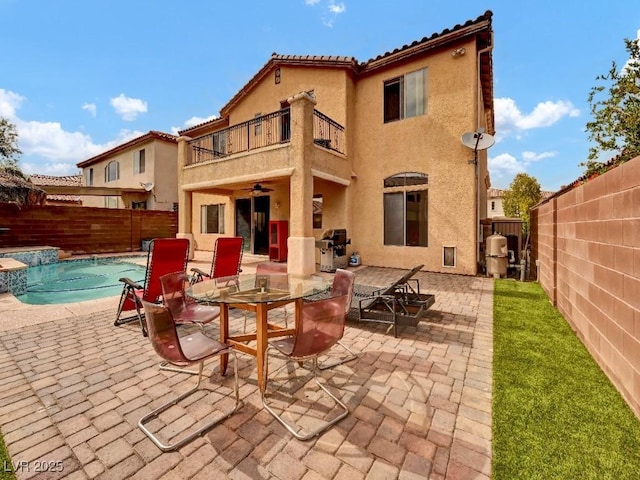 rear view of property featuring a fenced backyard, stucco siding, and a balcony