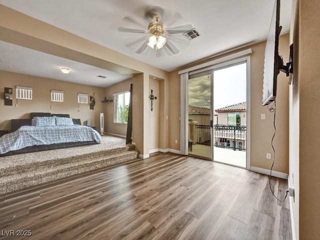 unfurnished bedroom with a ceiling fan, access to exterior, visible vents, wood finished floors, and baseboards