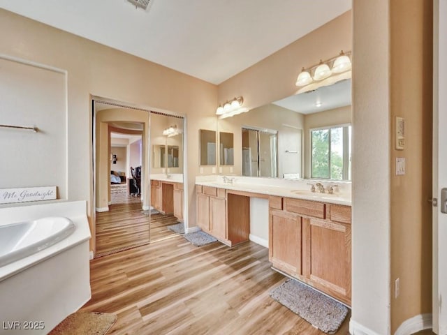 full bathroom with a sink, baseboards, double vanity, and wood finished floors
