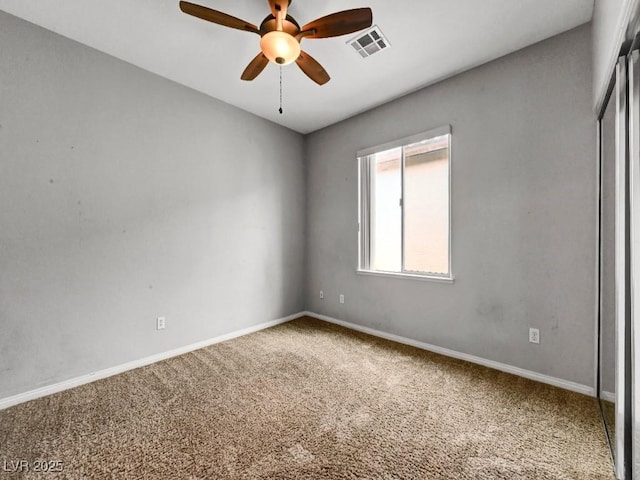 carpeted spare room featuring visible vents, a ceiling fan, and baseboards