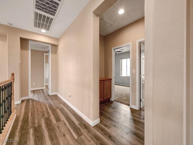 hallway featuring baseboards, recessed lighting, wood finished floors, and visible vents