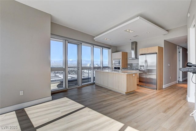 kitchen with light brown cabinetry, appliances with stainless steel finishes, ventilation hood, light wood-style flooring, and modern cabinets