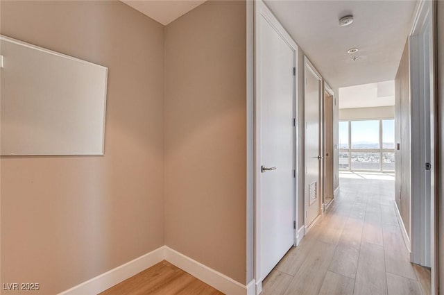 corridor featuring baseboards and light wood-type flooring