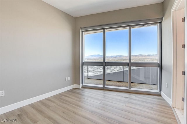 spare room featuring baseboards and light wood-type flooring