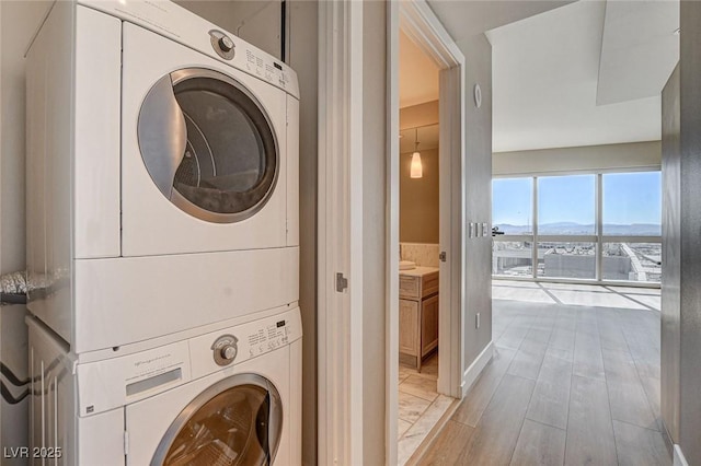 laundry area featuring a mountain view, stacked washer / dryer, and light wood-type flooring