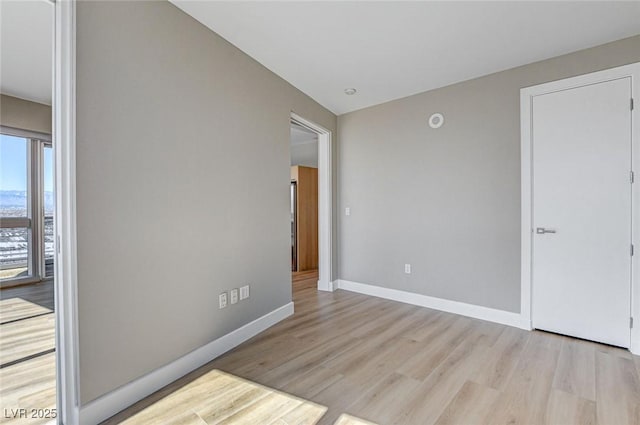 spare room featuring baseboards and wood finished floors