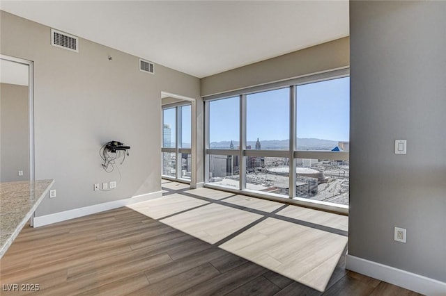spare room with baseboards, visible vents, a mountain view, and wood finished floors