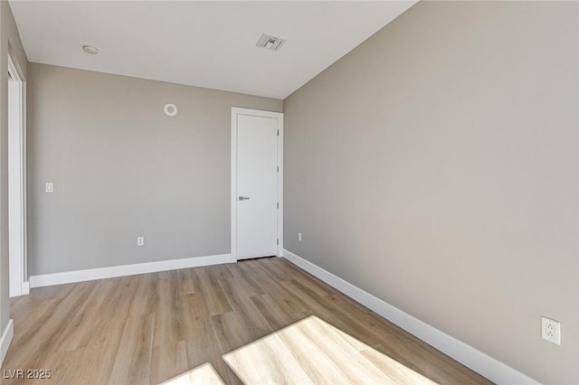 spare room with baseboards, visible vents, and wood finished floors