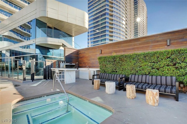 view of pool with an outdoor kitchen, exterior bar, an outdoor living space, a community hot tub, and a sink