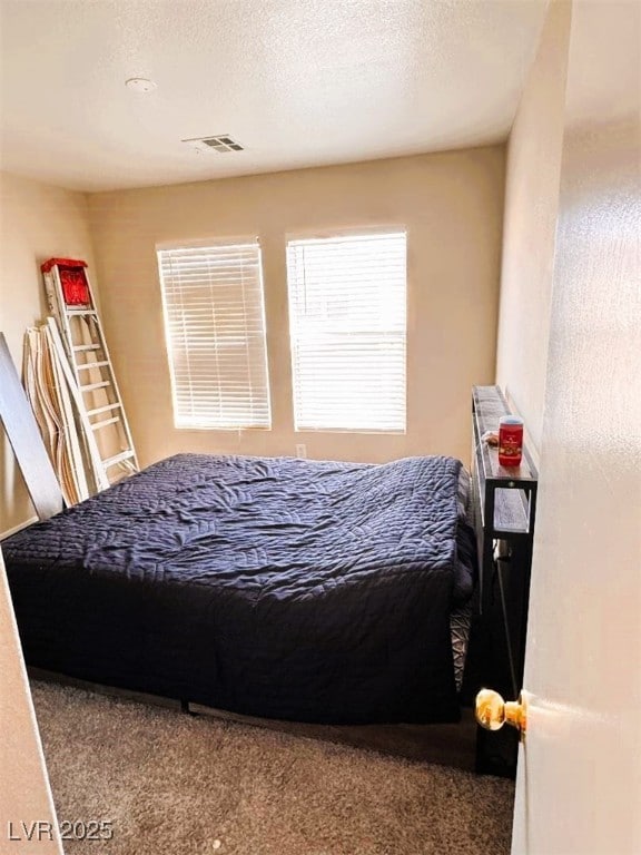 carpeted bedroom with a textured ceiling and visible vents