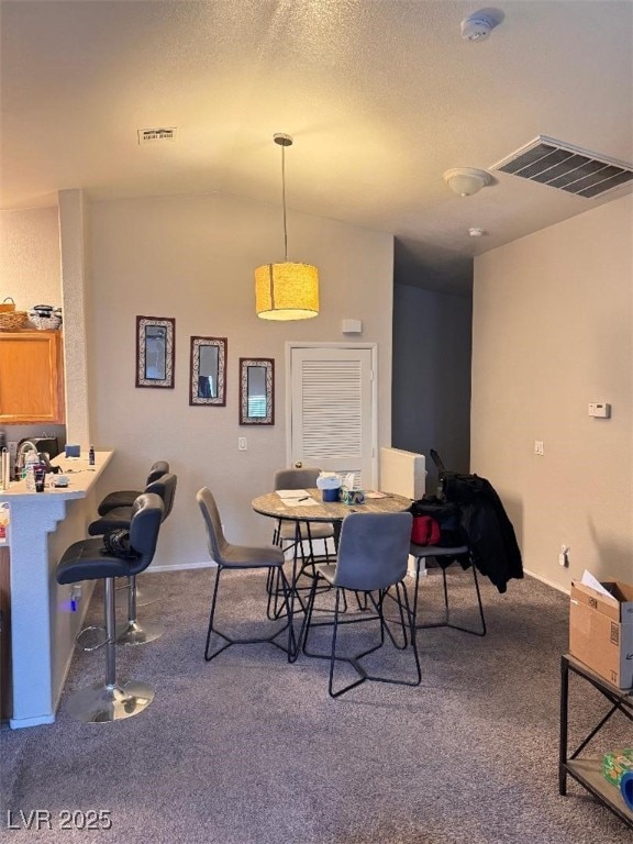 carpeted dining area featuring visible vents and lofted ceiling