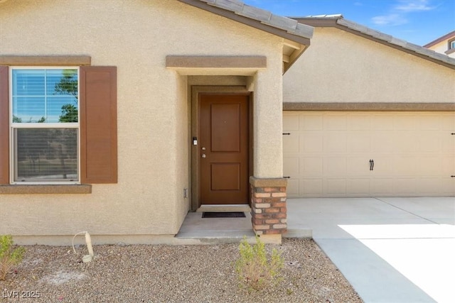 13 Deseo Ct, North Las Vegas, NV 89031 - view of exterior entry with a garage, stucco siding, and driveway