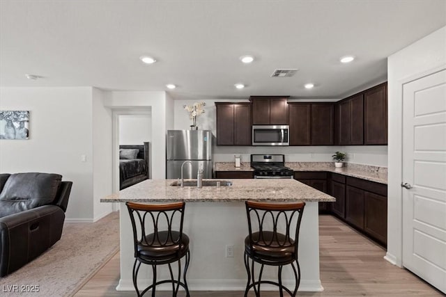 13 Deseo Ct, North Las Vegas, NV 89031 - kitchen with visible vents, a breakfast bar, open floor plan, a sink, and stainless steel appliances