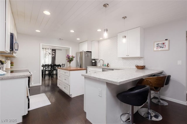 kitchen with recessed lighting, white cabinets, a sink, backsplash, and stainless steel appliances