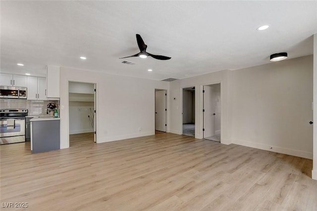 unfurnished living room featuring light wood-style floors, a ceiling fan, baseboards, recessed lighting, and visible vents