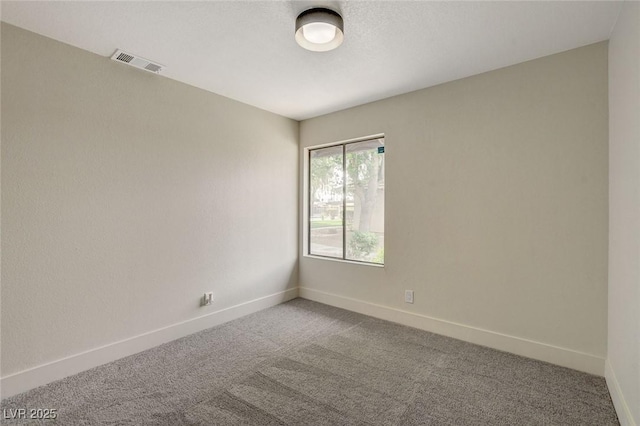 spare room featuring carpet floors, baseboards, and visible vents
