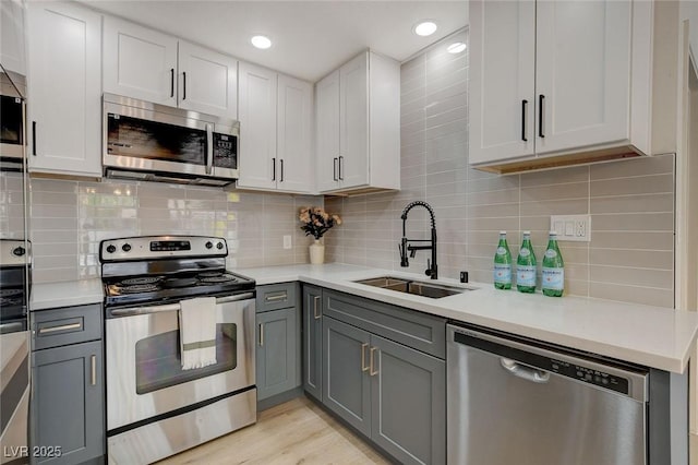 kitchen with light countertops, gray cabinets, appliances with stainless steel finishes, and a sink