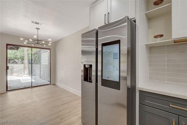 kitchen featuring visible vents, open shelves, stainless steel fridge with ice dispenser, baseboards, and light wood finished floors
