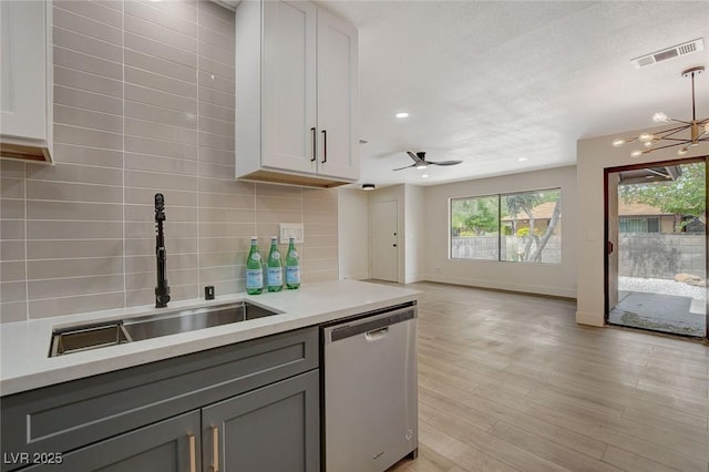 kitchen featuring stainless steel dishwasher, a sink, gray cabinets, and visible vents